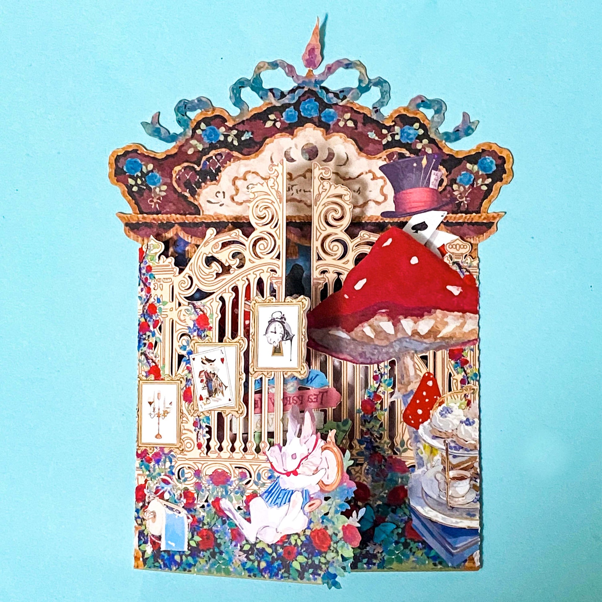 alice in wonderland themed pop up 3d greeting card with tea party scene, white rabbit, mushroom, playing cards and layered theatrical paper design.