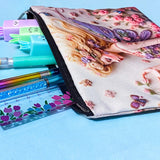 fairy garden canvas zip pouch with floral illustration and butterfly wings used as a pencil case on a blue background