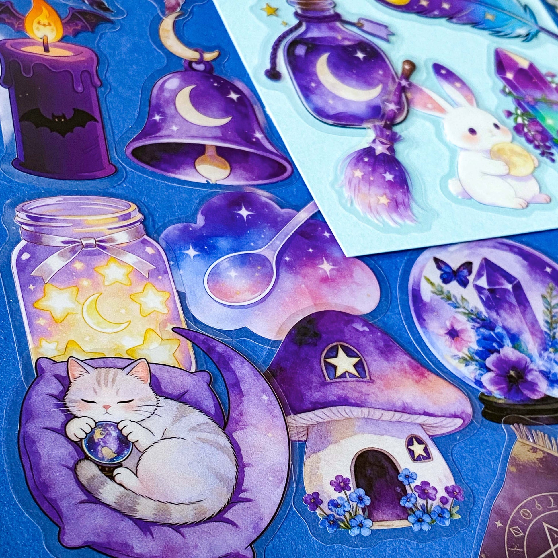 pack of 50 magical fantasy stickers featuring crystal balls, spell books, moonlit scrolls, enchanted mushrooms, ravens, potion bottles, celestial moons, magical animals and crystal gardens in lavender, violet and blue tones. UK stationery shop and letterbox gifts store.