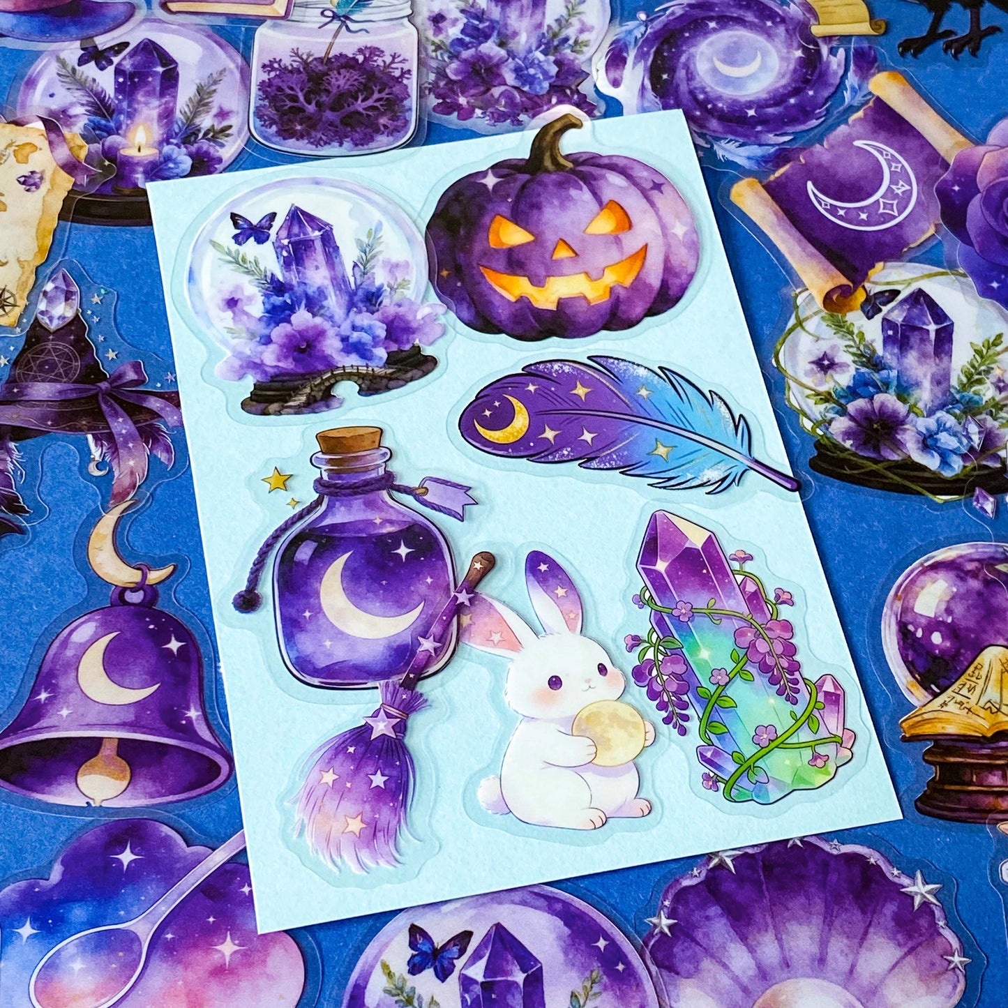 pack of 50 magical fantasy stickers featuring crystal balls, spell books, moonlit scrolls, enchanted mushrooms, ravens, potion bottles, celestial moons, magical animals and crystal gardens in lavender, violet and blue tones. UK stationery shop and letterbox gifts store.