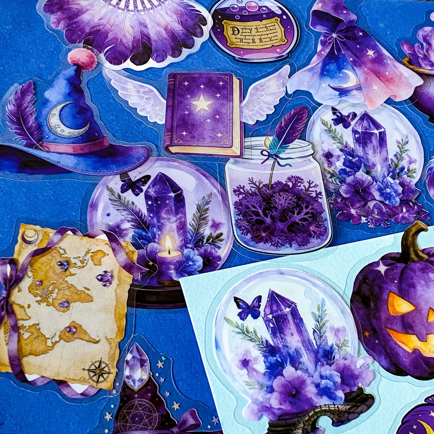 pack of 50 magical fantasy stickers featuring crystal balls, spell books, moonlit scrolls, enchanted mushrooms, ravens, potion bottles, celestial moons, magical animals and crystal gardens in lavender, violet and blue tones. UK stationery shop and letterbox gifts store.