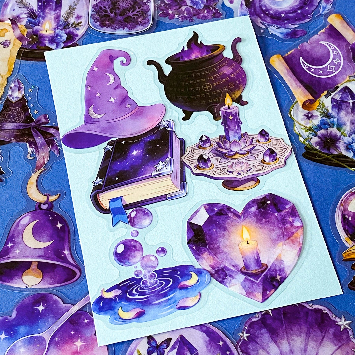 pack of 50 magical fantasy stickers featuring crystal balls, spell books, moonlit scrolls, enchanted mushrooms, ravens, potion bottles, celestial moons, magical animals and crystal gardens in lavender, violet and blue tones. UK stationery shop and letterbox gifts store.