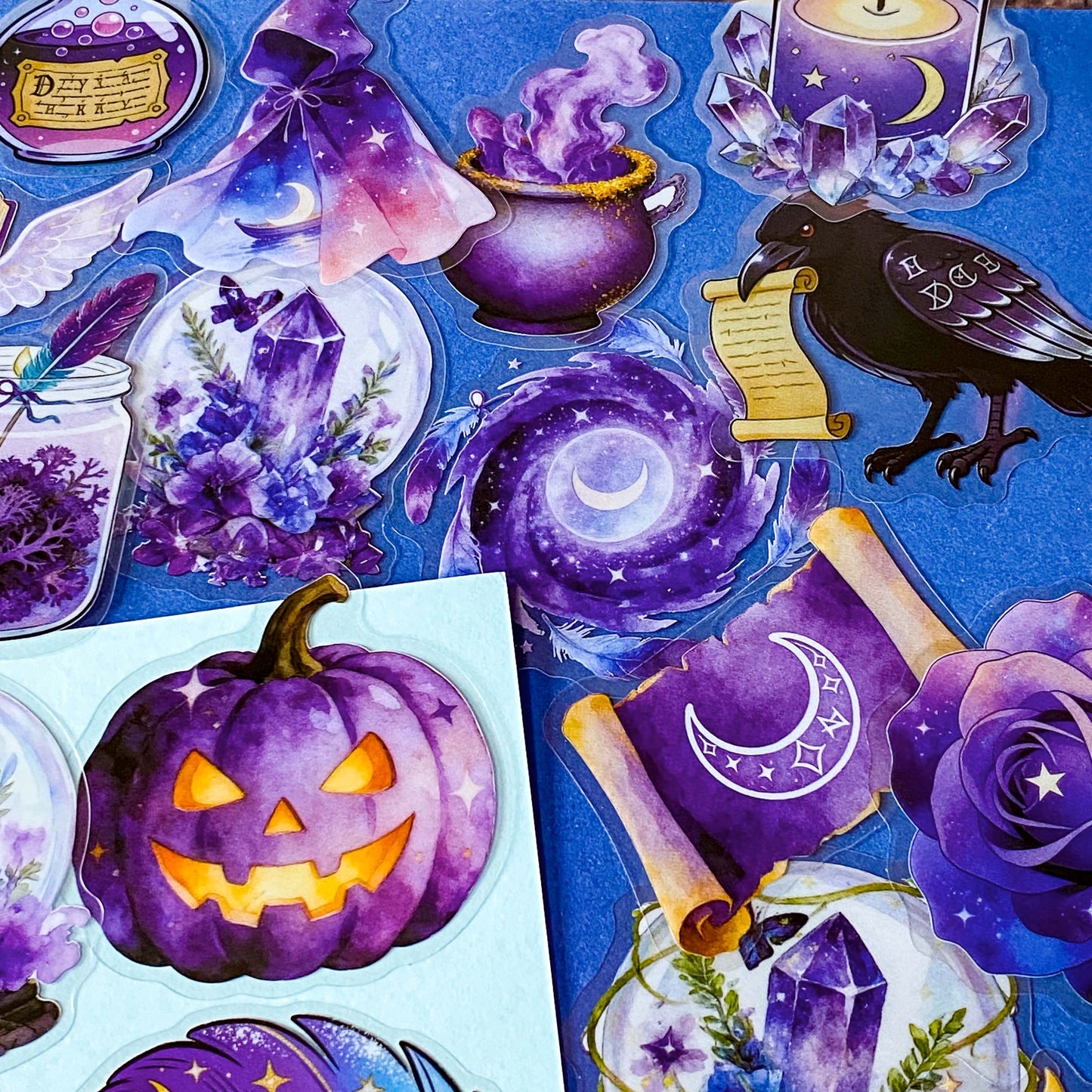 pack of 50 magical fantasy stickers featuring crystal balls, spell books, moonlit scrolls, enchanted mushrooms, ravens, potion bottles, celestial moons, magical animals and crystal gardens in lavender, violet and blue tones. UK stationery shop and letterbox gifts store.
