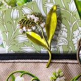 lily of the valley botanical gift set including floral zip canvas pouch, articulated lily of the valley metal brooch, botanical glass cabochon bookmark, floral mini notebook, black ornate ballpoint pen and pack of 6 clear PET lily of the valley large sticker sheets. Green, natural cream and white coloured set. Uk letterbox gift shop for vintage and beautiful gifts and keepsakes.