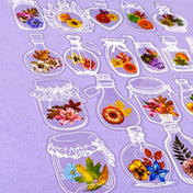 Decorative clear plastic pet stickers of flowers in glass jars on a purple background