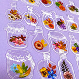 Decorative clear plastic stickers of flowers in glass jars on a purple background