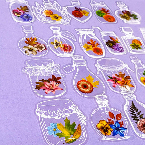 Decorative clear plastic pet stickers of flowers in glass jars on a purple background