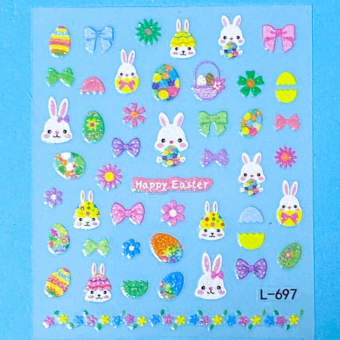 Sheet of Easter-themed glittery nail art stickers with bunnies, eggs, and flowers on a blue background.