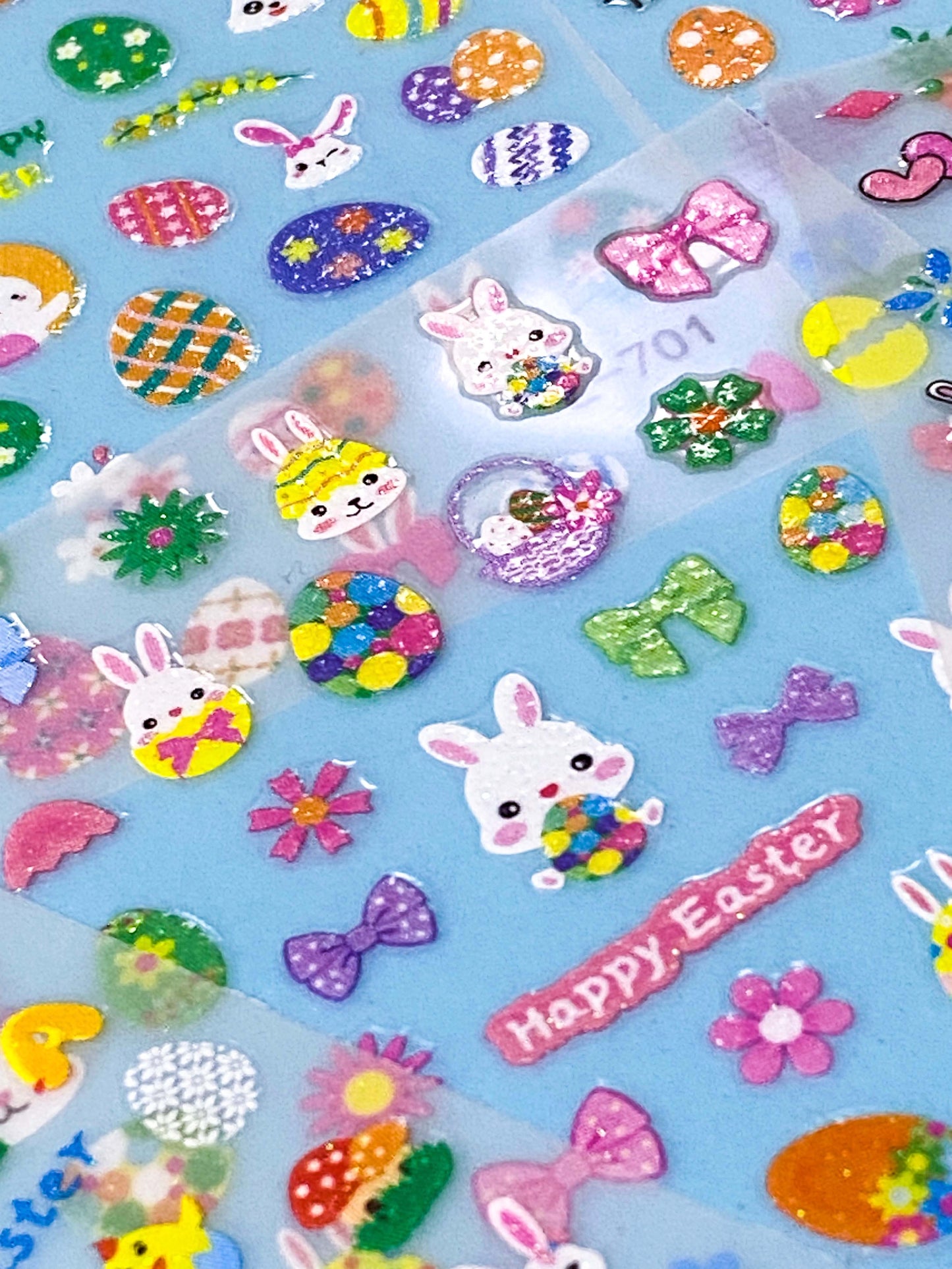 Colourful Easter-themed nail art glittery stickers on a blue background