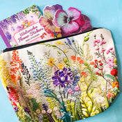 floral gift set with illustrated flower pouch, watercolour sticker book and purple enamel flower brooch on a blue background