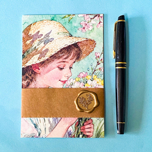 set of spring pastel postcards wrapped in a kraft belly band with wax seal sticker on a blue background