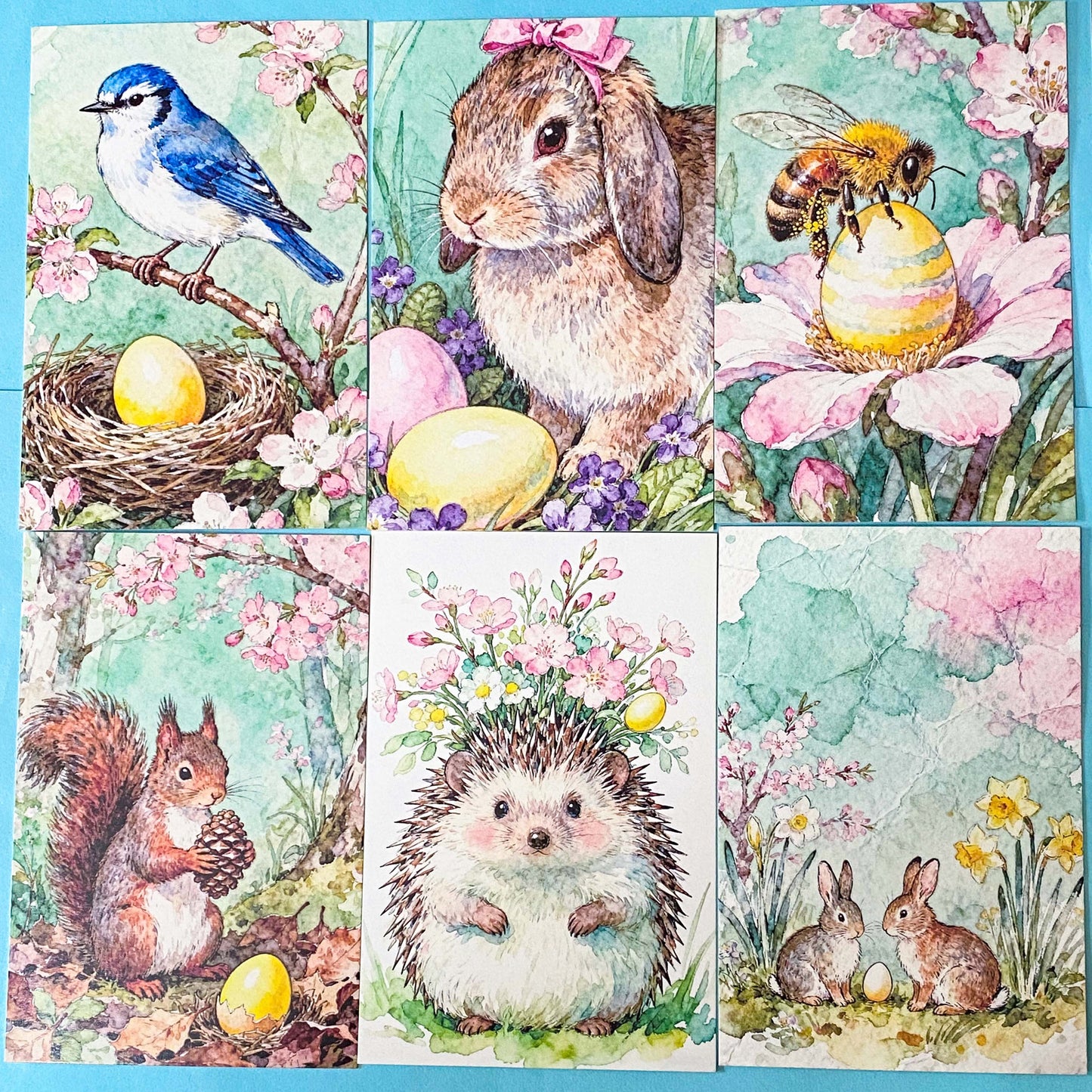 set of 6 spring animal postcards featuring bunny, blue bird, bee, squirrel and hedgehog illustrations with blossom flowers,