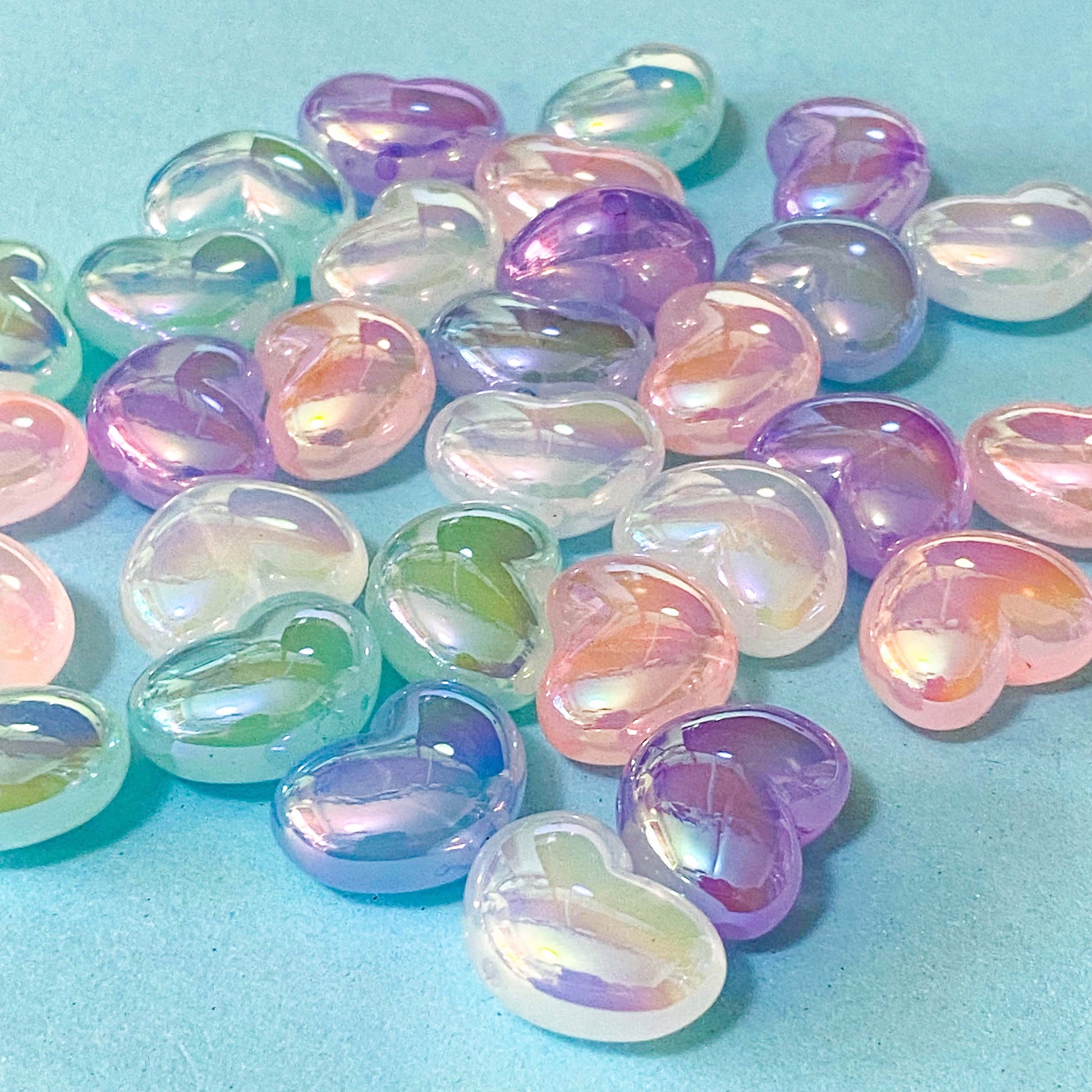 Iridescent heart-shaped beads on a light blue background