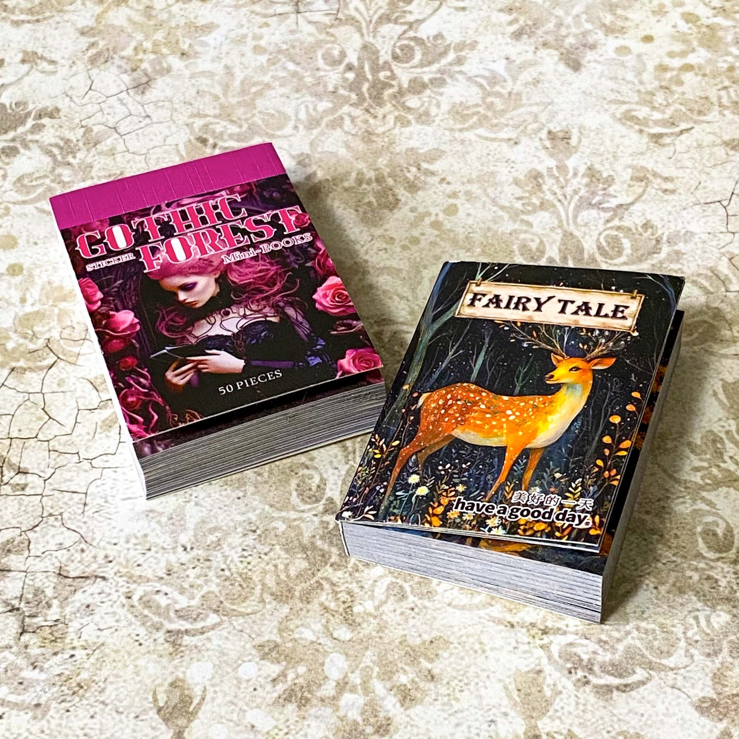 two mini sticker books in gothic forest and fairytale deer designs on a vintage patterned background