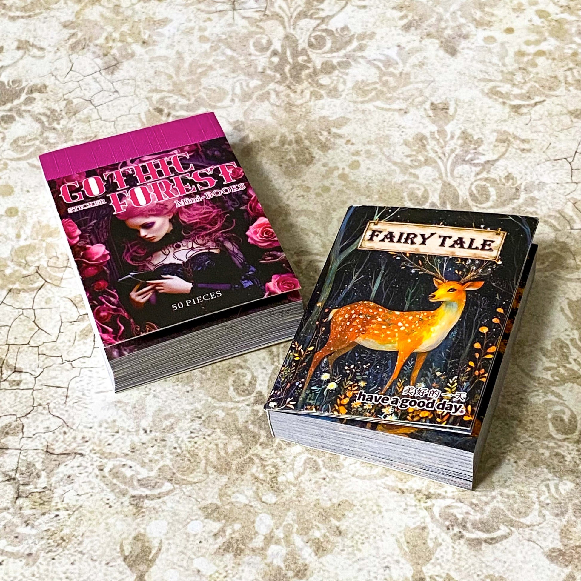 two mini sticker books in gothic forest and fairytale deer designs on a vintage patterned background