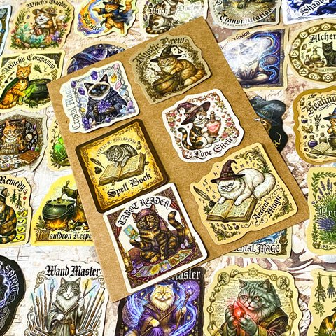 glossy witchy cat stickers spread out showing magical designs including potion cats, astrology, spell books and crystal ball illustrations in vintage style