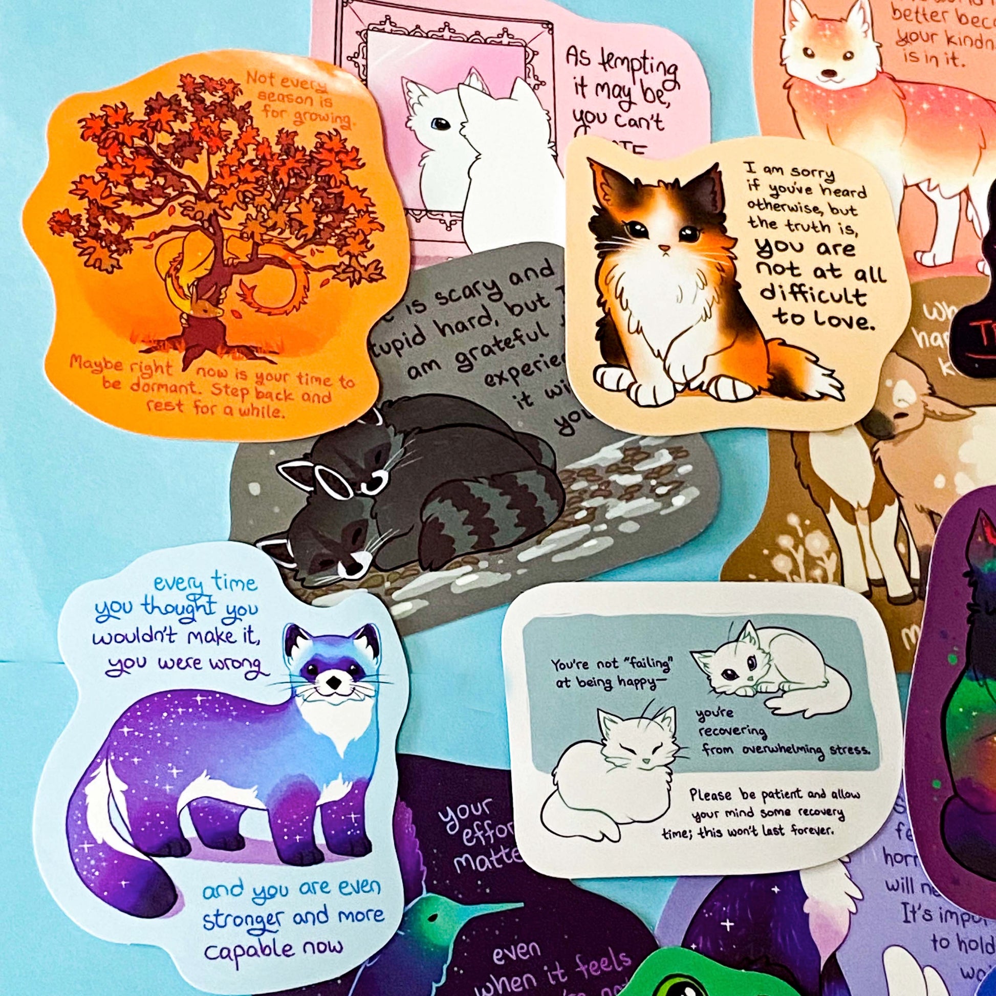 colourful glossy affirmation stickers with cute animals and positive mental health messages including dragon, cat, stoat and magical creatures on pastel background