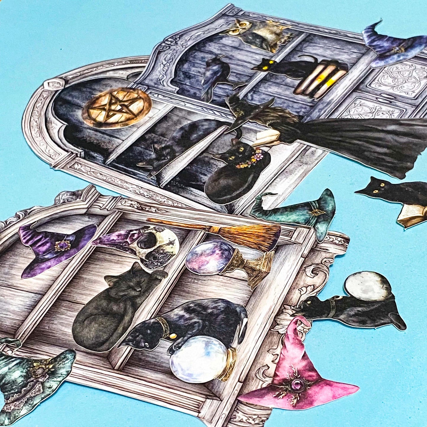 witch cabinet of curiosities ephemera pack with black cats, spell books, crystal balls and gothic shelves on blue background