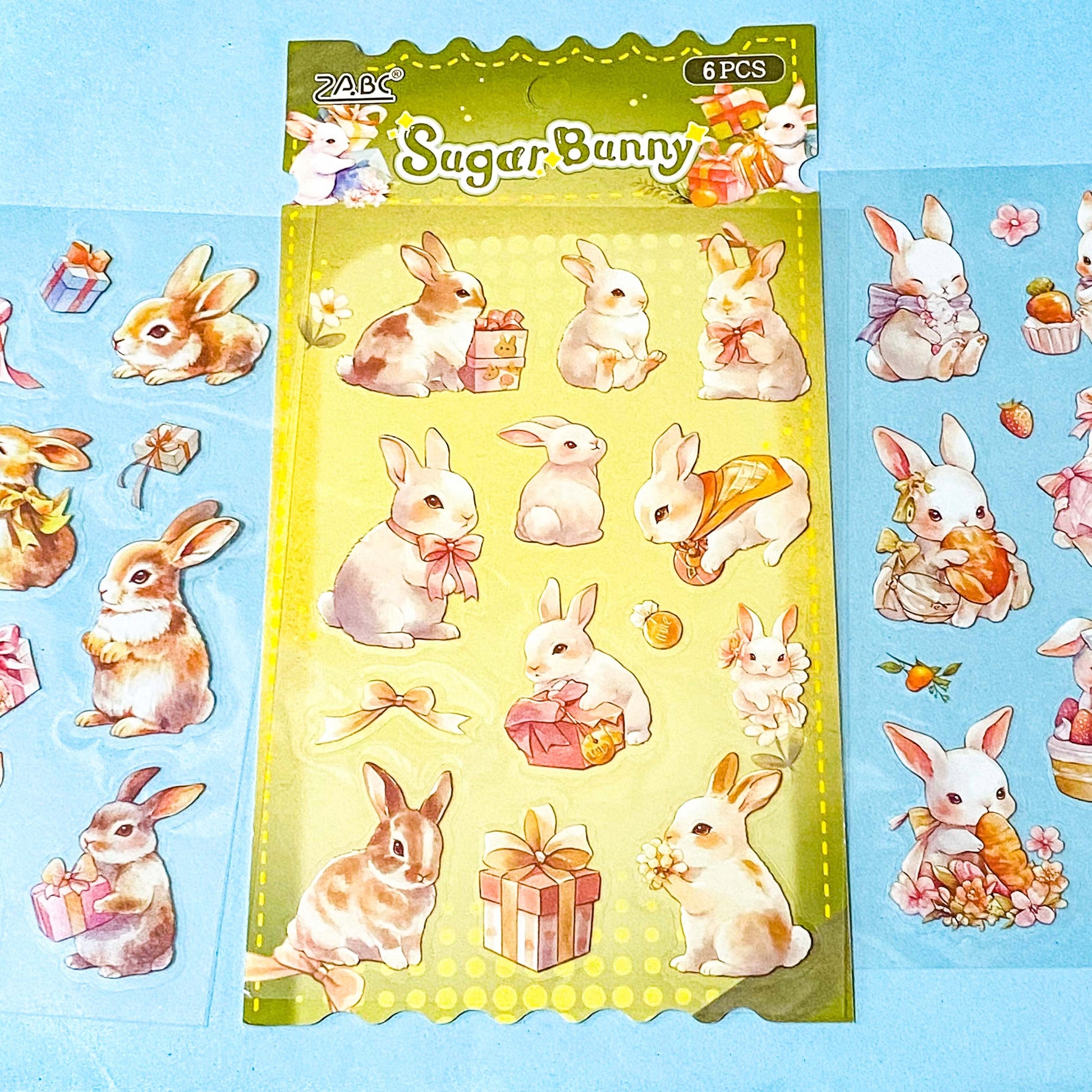 set of 6 kawaii bunny clear plastic sticker sheets with pastel rabbits, flowers and gift illustrations on a blue background
