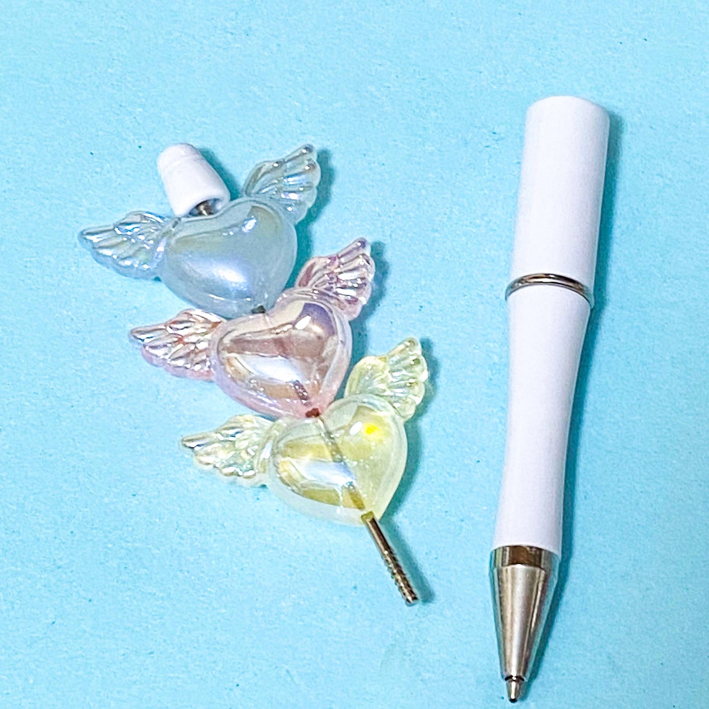 white pen base with winged heart large acrylic beads on a blue background