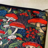 deep red canvas mushroom zip pouch featuring red toadstools, berries and botanical foliage on a dark forest background. Uk gift shop for letterbox gifts.