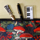 deep red canvas mushroom zip pouch featuring red toadstools, berries and botanical foliage on a dark forest background. Uk gift shop for letterbox gifts.