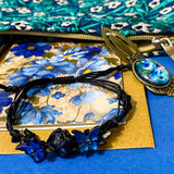 midnight petals letterbox gift set featuring a dark blue and green floral tapestry pouch, botanical ballpoint pen, blank flower greetings card and envelope, floral crystal and butterfly bracelet and dark floral clear sticker pack. uk cute and beautiful gift shop.