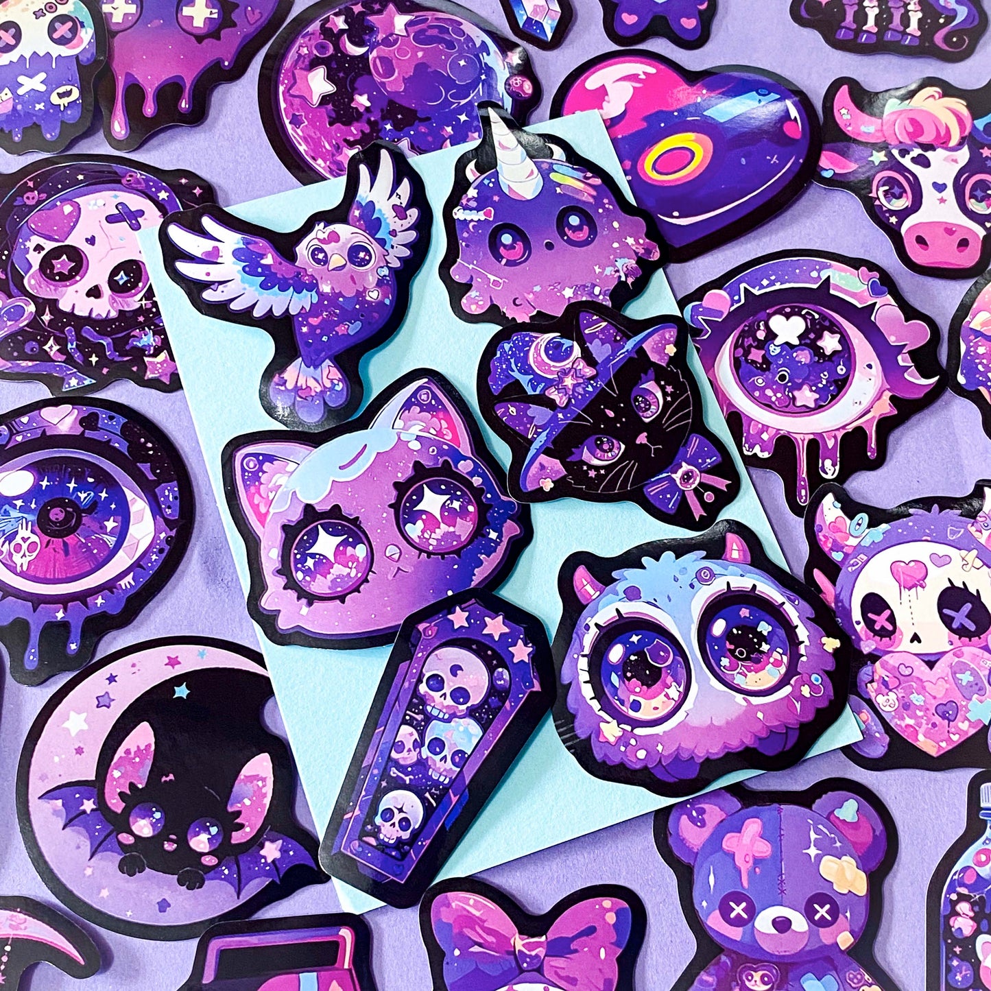 pack of 50 large glossy laptop stickers featuring bats, skulls, moons, owls, eyes, cows, unicorns, potion bottles, crystals, celestial artwork in purple, pink , lilac and blue tones. vibrant pack. uk cute stickers shop.