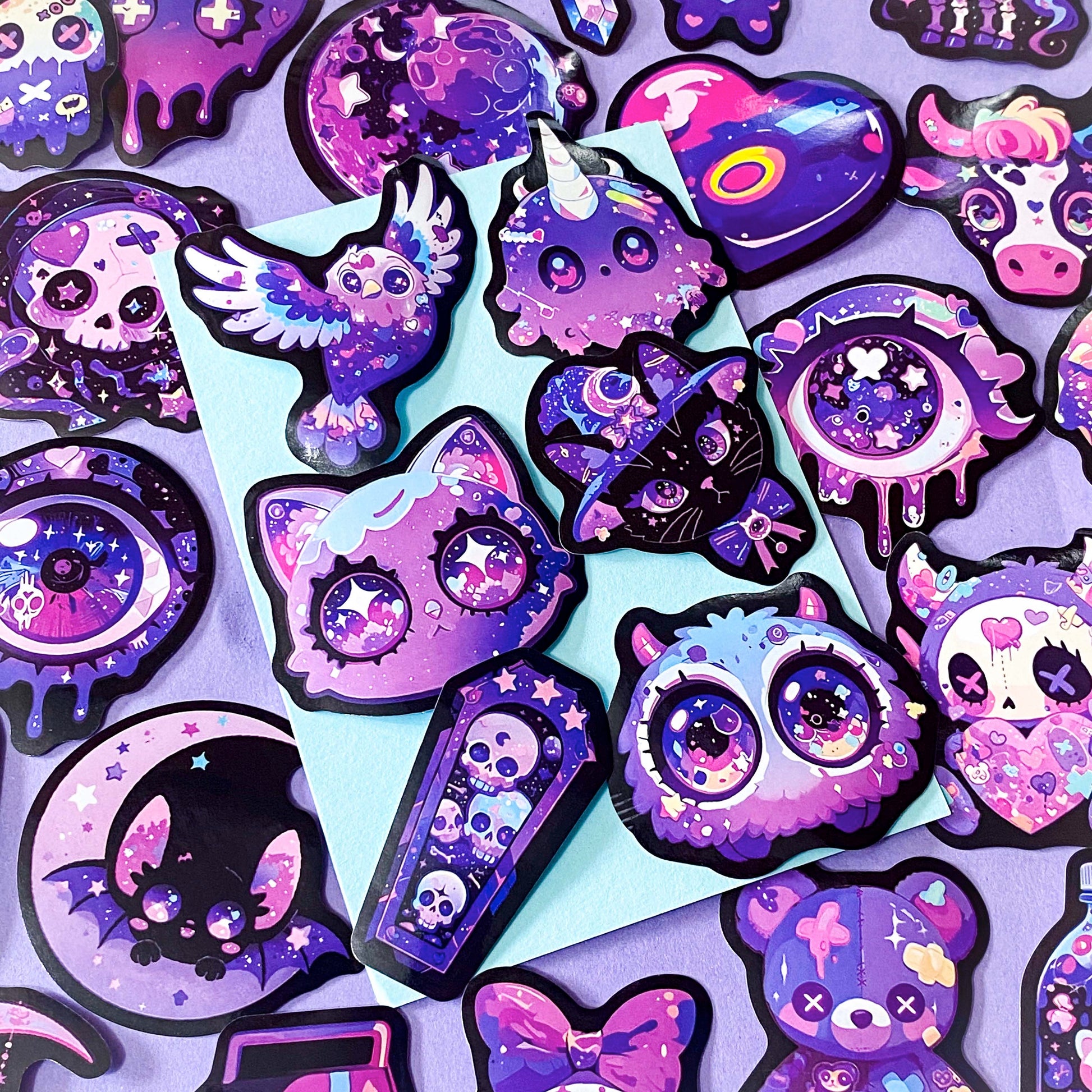 pack of 50 large glossy laptop stickers featuring bats, skulls, moons, owls, eyes, cows, unicorns, potion bottles, crystals, celestial artwork in purple, pink , lilac and blue tones. vibrant pack. uk cute stickers shop.