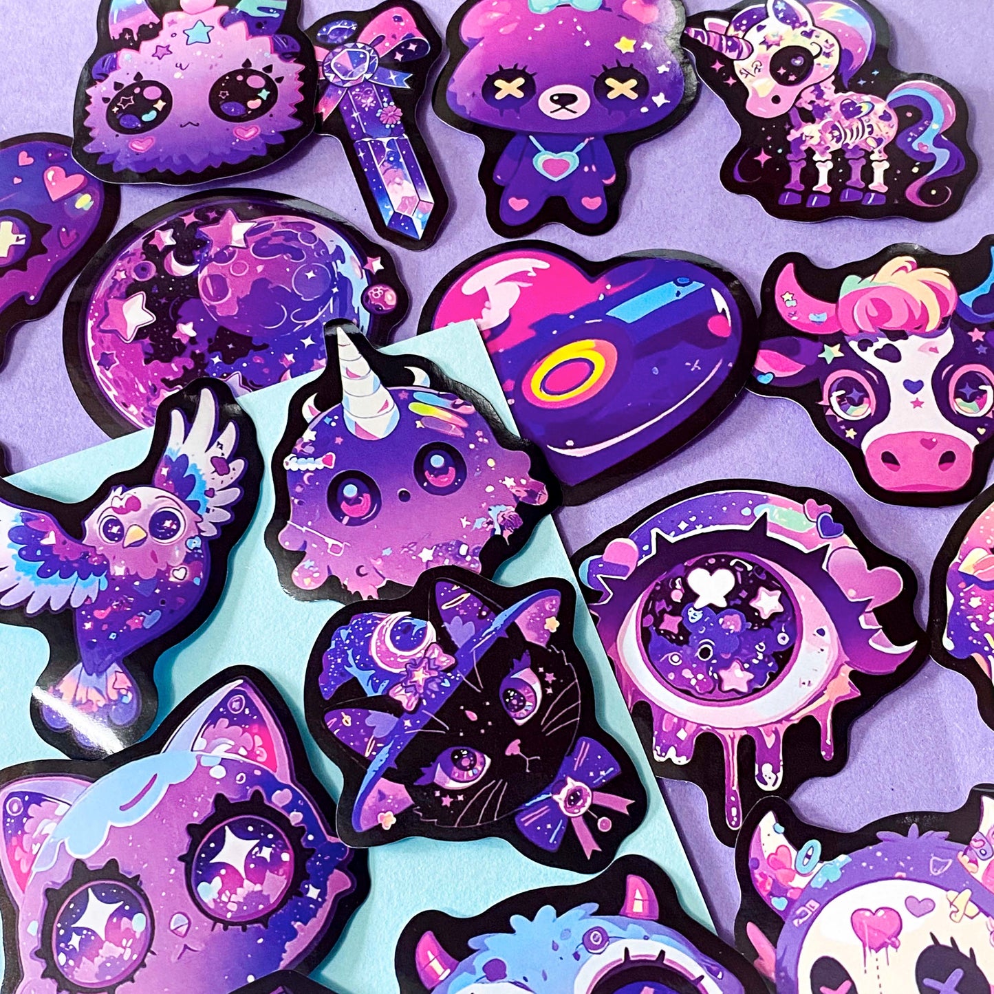 pack of 50 large glossy laptop stickers featuring bats, skulls, moons, owls, eyes, cows, unicorns, potion bottles, crystals, celestial artwork in purple, pink , lilac and blue tones. vibrant pack. uk cute stickers shop.