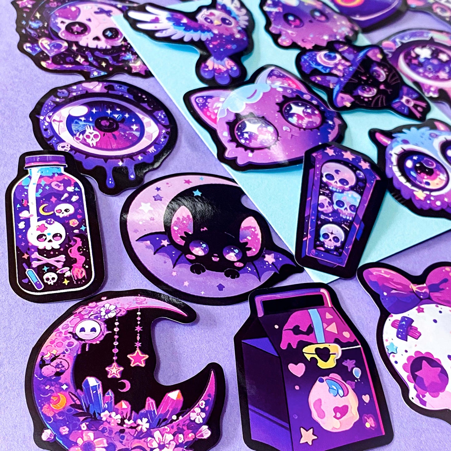 pack of 50 large glossy laptop stickers featuring bats, skulls, moons, owls, eyes, cows, unicorns, potion bottles, crystals, celestial artwork in purple, pink , lilac and blue tones. vibrant pack. uk cute stickers shop.