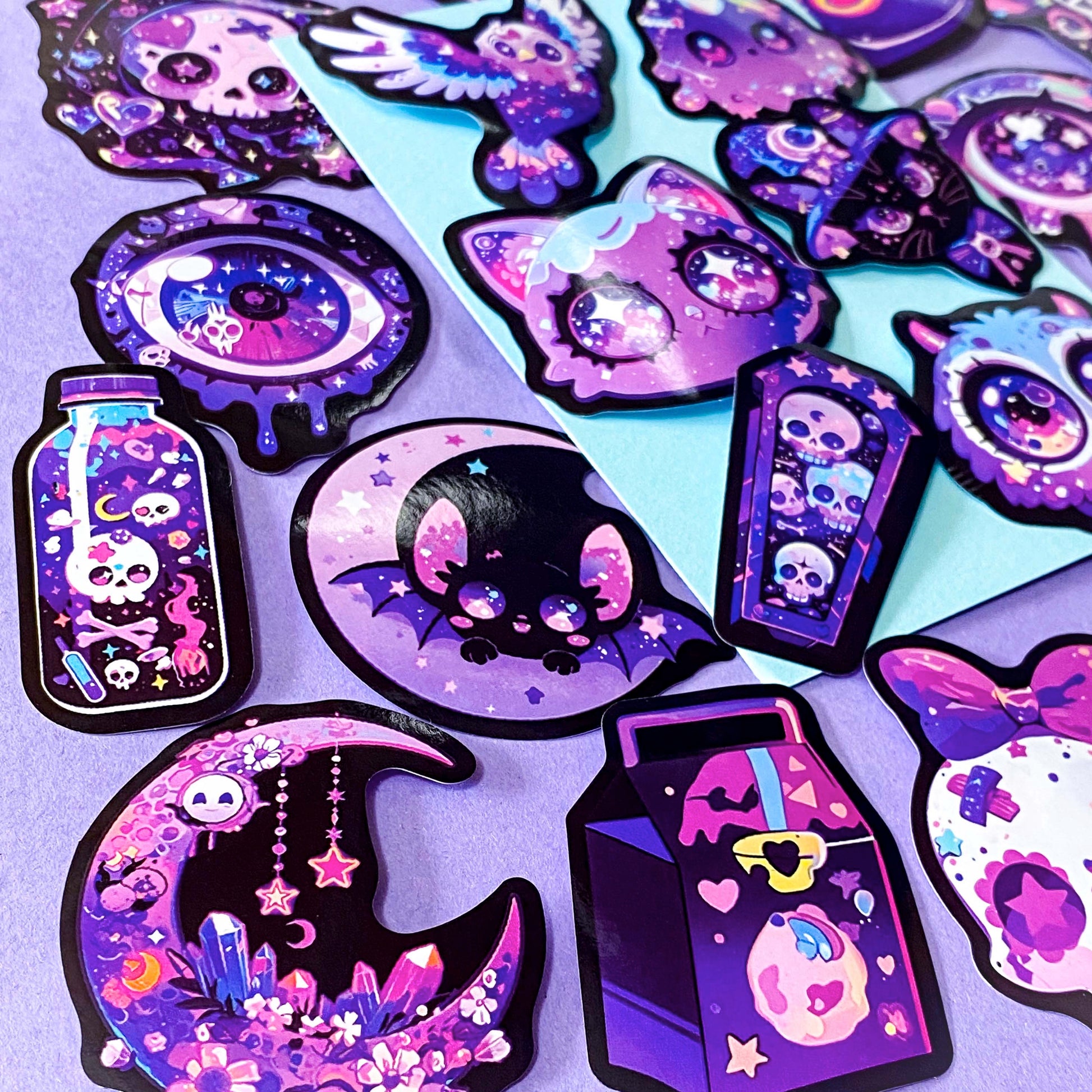 pack of 50 large glossy laptop stickers featuring bats, skulls, moons, owls, eyes, cows, unicorns, potion bottles, crystals, celestial artwork in purple, pink , lilac and blue tones. vibrant pack. uk cute stickers shop.