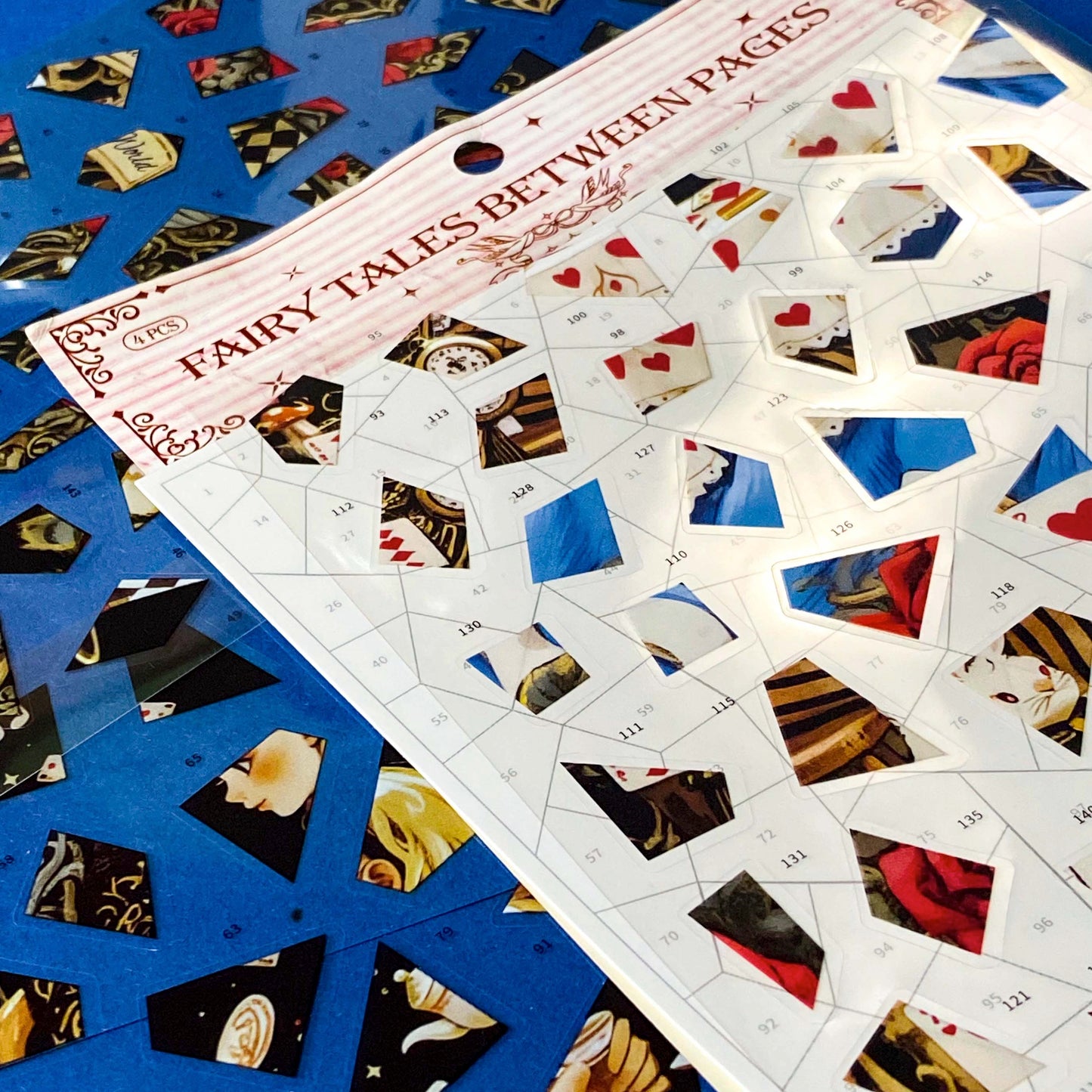 alice in wonderland inspired mosaic puzzle sticker craft kit with numbered template sheet and transparent PET sticker pieces revealing a whimsical tea party illustration