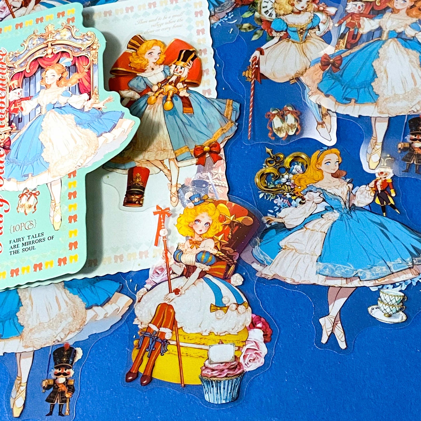 large nutcracker- inspired clear PET sticker pack featuring ballet princess illustrations, toy soldiers, ribbons, clocks and ornate storybook artwork in blue and gold tones with red.