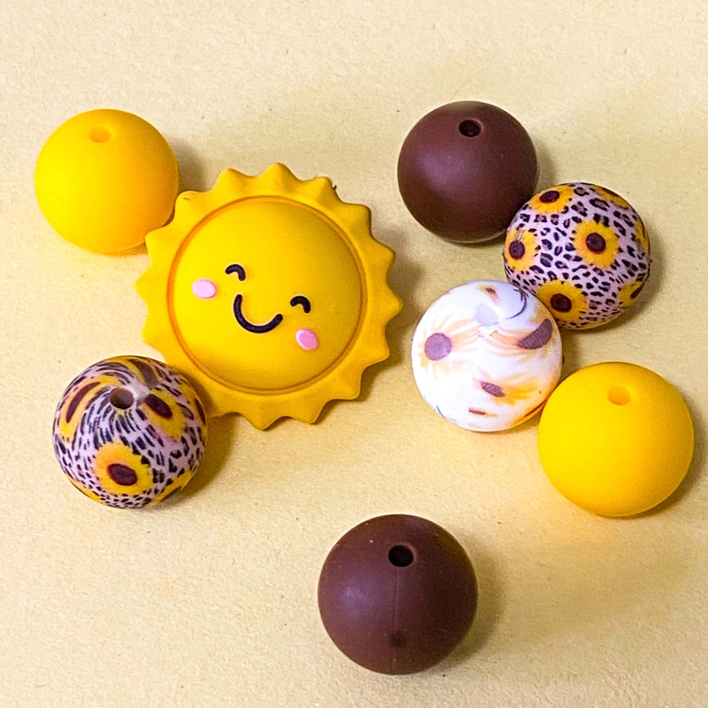 sunny yellow and dark brown silicone beads mix with sunshine jumbo 27mm focal bead and patterned sunflower design 16mm beads. uk craft supplies shop.