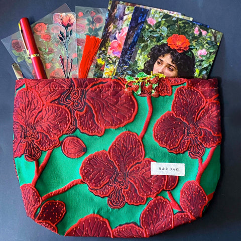 strawberries and red roses letterbox gift set featuring a lined emerald green and crimson floral pouch, rose sticker sheets, floral acrylic bookmark with tassel, red metallic pen, romantic postcards and enamel strawberry brooch. Uk letterbox gifts shop.