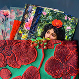 strawberries and red roses letterbox gift set featuring a lined emerald green and crimson floral pouch, rose sticker sheets, floral acrylic bookmark with tassel, red metallic pen, romantic postcards and enamel strawberry brooch. Uk letterbox gifts shop.