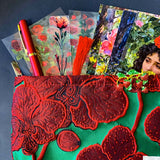 strawberries and red roses letterbox gift set featuring a lined emerald green and crimson floral pouch, rose sticker sheets, floral acrylic bookmark with tassel, red metallic pen, romantic postcards and enamel strawberry brooch. Uk letterbox gifts shop.