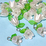 white pearl flower and leaf charms with silver tone hooks on a blue background 