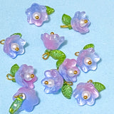 Decorative flower charms in lilac and pink acrylic  with green leaves on a light blue background