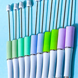 pastel beaded pen bases in sage, mint, periwinkle, lime and lavender on a blue background