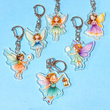fairy keychains with acrylic charms and silver clips on a blue background