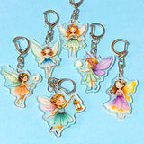 fairy keychains with acrylic charms and silver clips on a blue background