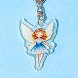 Fairy keychain with a blue dress on a light blue background