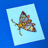 colourful moth embroidered applique patch to sew or iron on to fabric on a blue background