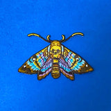 colourful moth embroidered applique patch to sew or iron on to fabric on a blue background