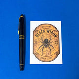 vintage style black widow spider potion bottle label on a blue background