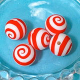 Red and white striped silicone beads on a blue glass plate