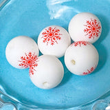 White silicone beads with red snowflake patterns on a blue surface