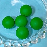 dark Green silicone beads on a clear glass plate with a blue background